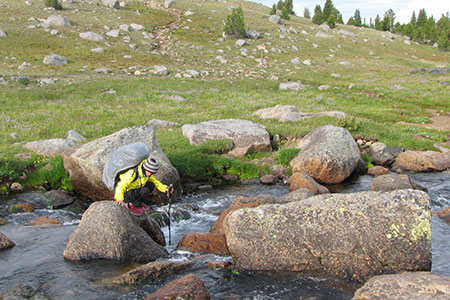 Hiker crossing Washakie Creek on boulders