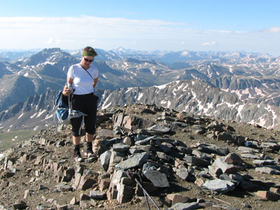 Amy on top of a mountain taking her pack off